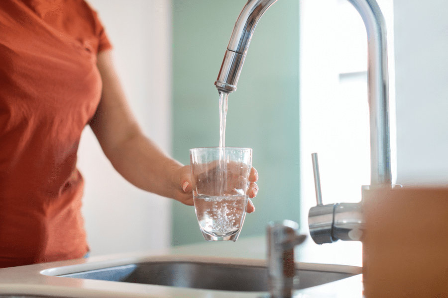 Woman filling up a glass of water at sink