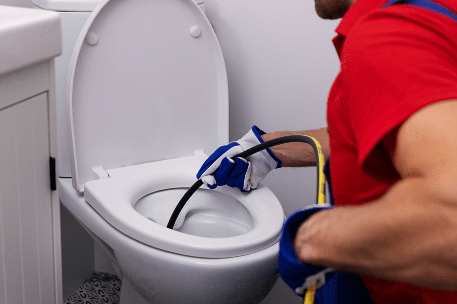 a Chipper Plumbing specialist in red shirt fixing toilet
