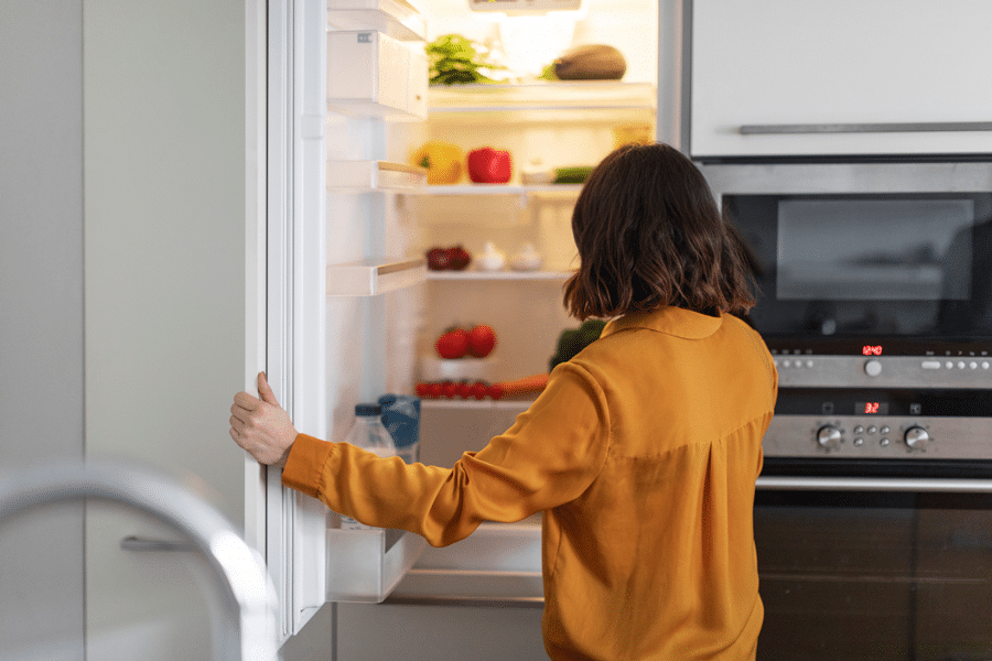 Woman in yellow shirt opening fridge
