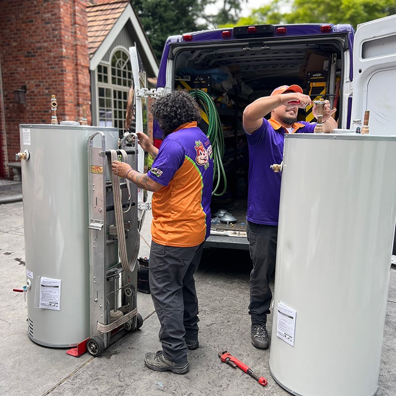 two Chipper Plumbing experts prepping water heaters outside