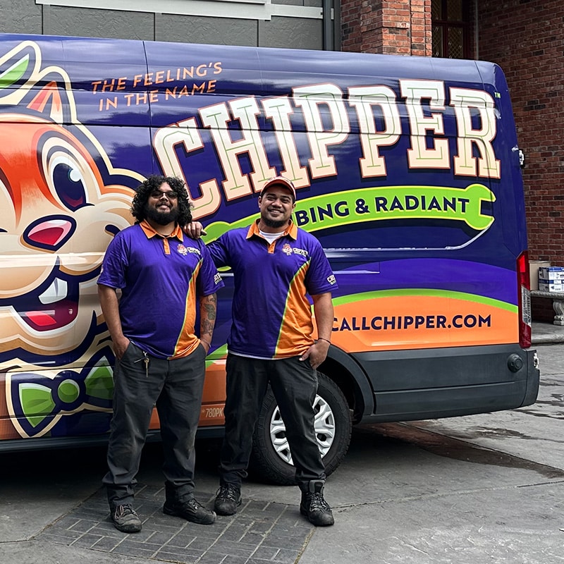 two Chipper Plumbing experts standing next to the van outside of a client's home