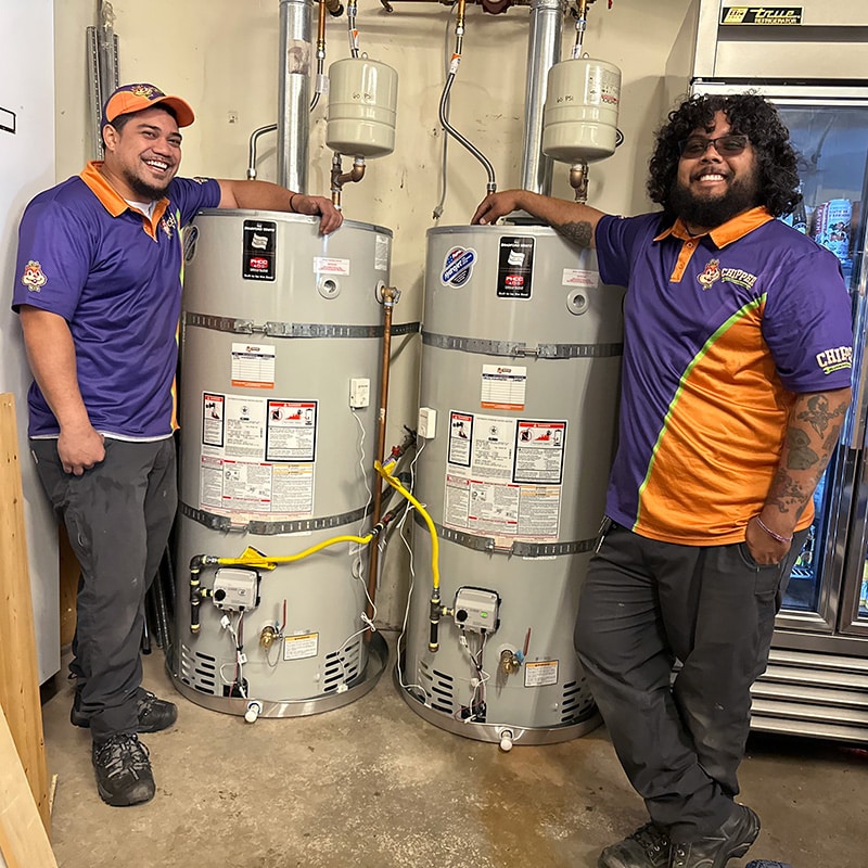 two Chipper Plumbing experts standing next to two recently installed water heaters