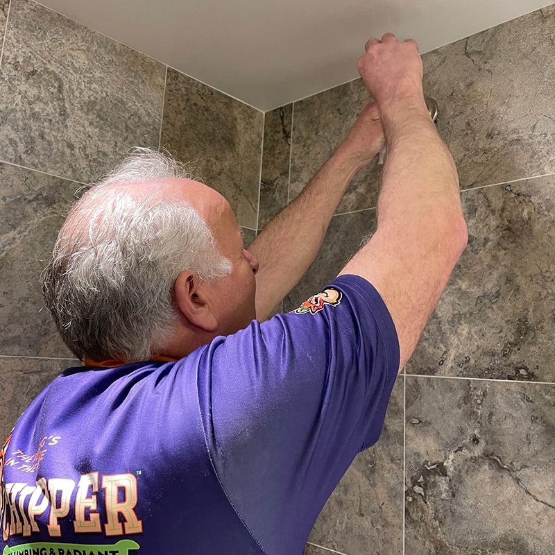 a Chipper Plumbing expert at work on a residential shower