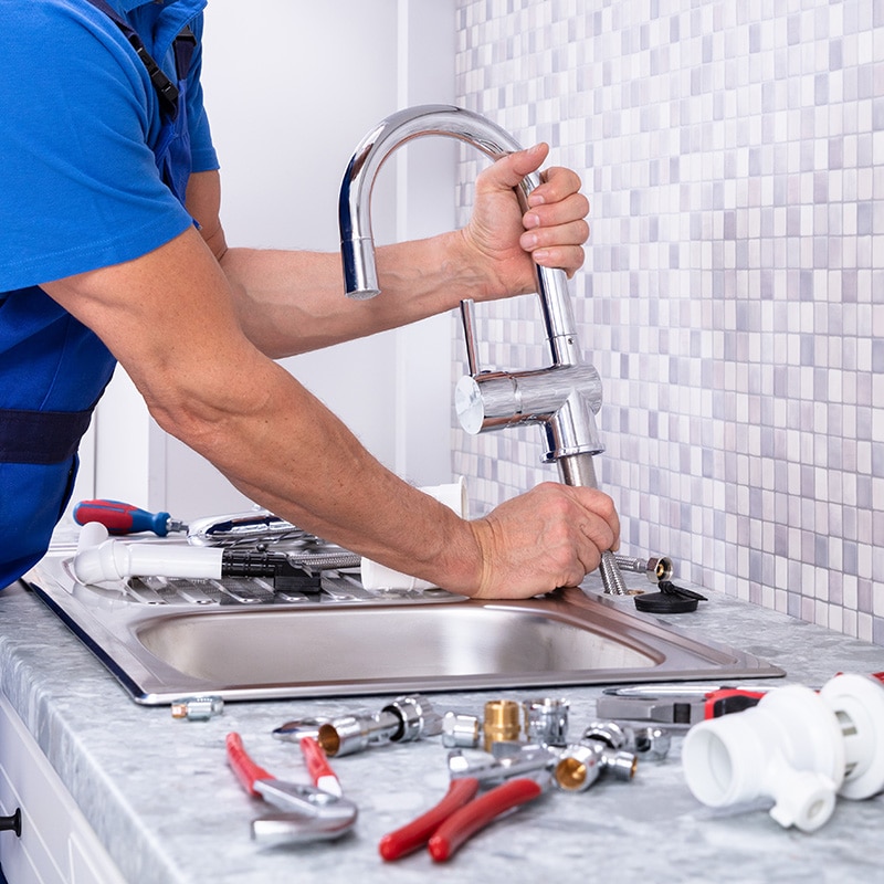 a Chipper Plumbing specialist installing a kitchen faucet