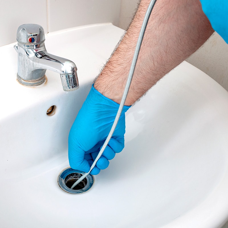 a Chipper Plumbing & Radiant specialist clearing a sink drain with a snake tool