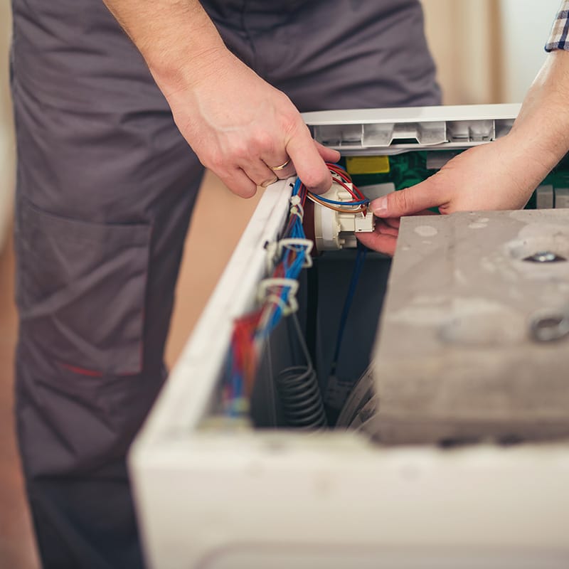 a Chipper Plumbing appliance expert managing wiring in a washing machine